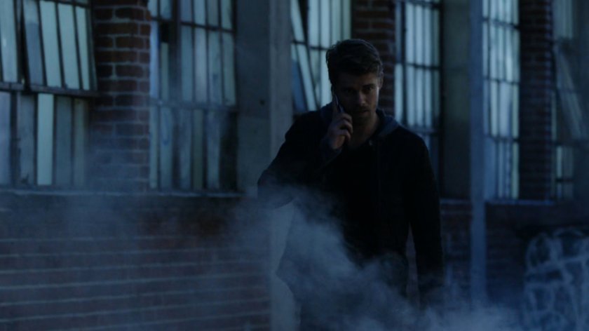 Lincoln on the phone, walking along a dark sidewalk.