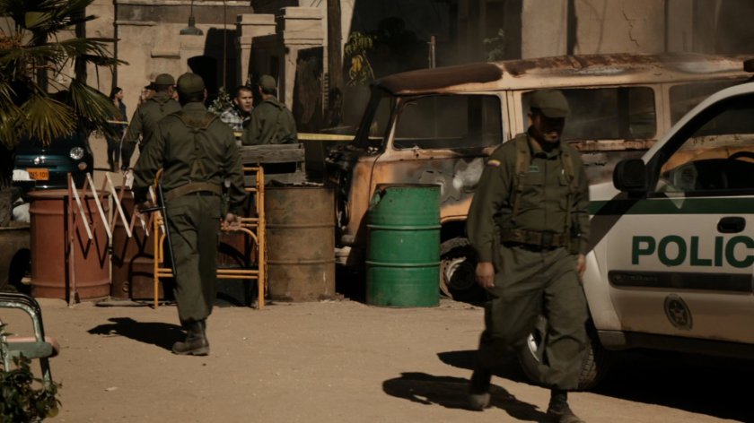 Police officers clean up burned vehicle on Bogota street.