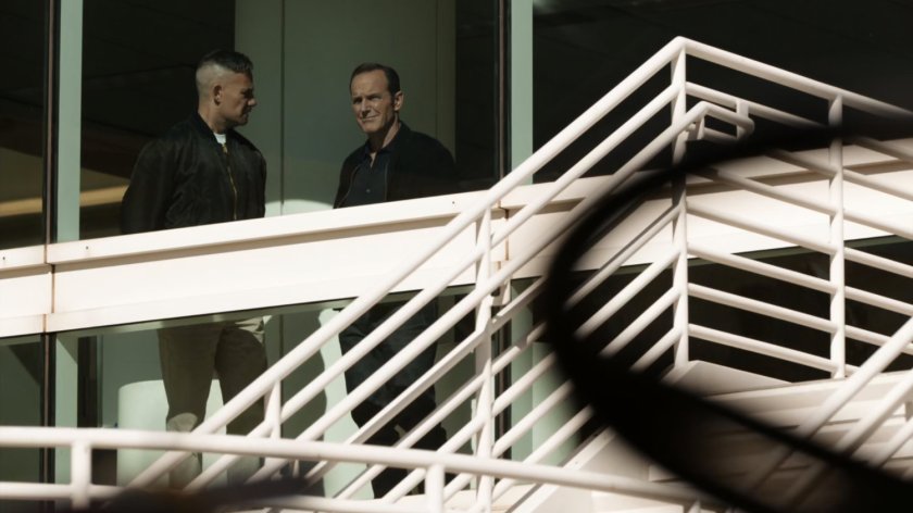 Talbot and Coulson standing at window in airport.