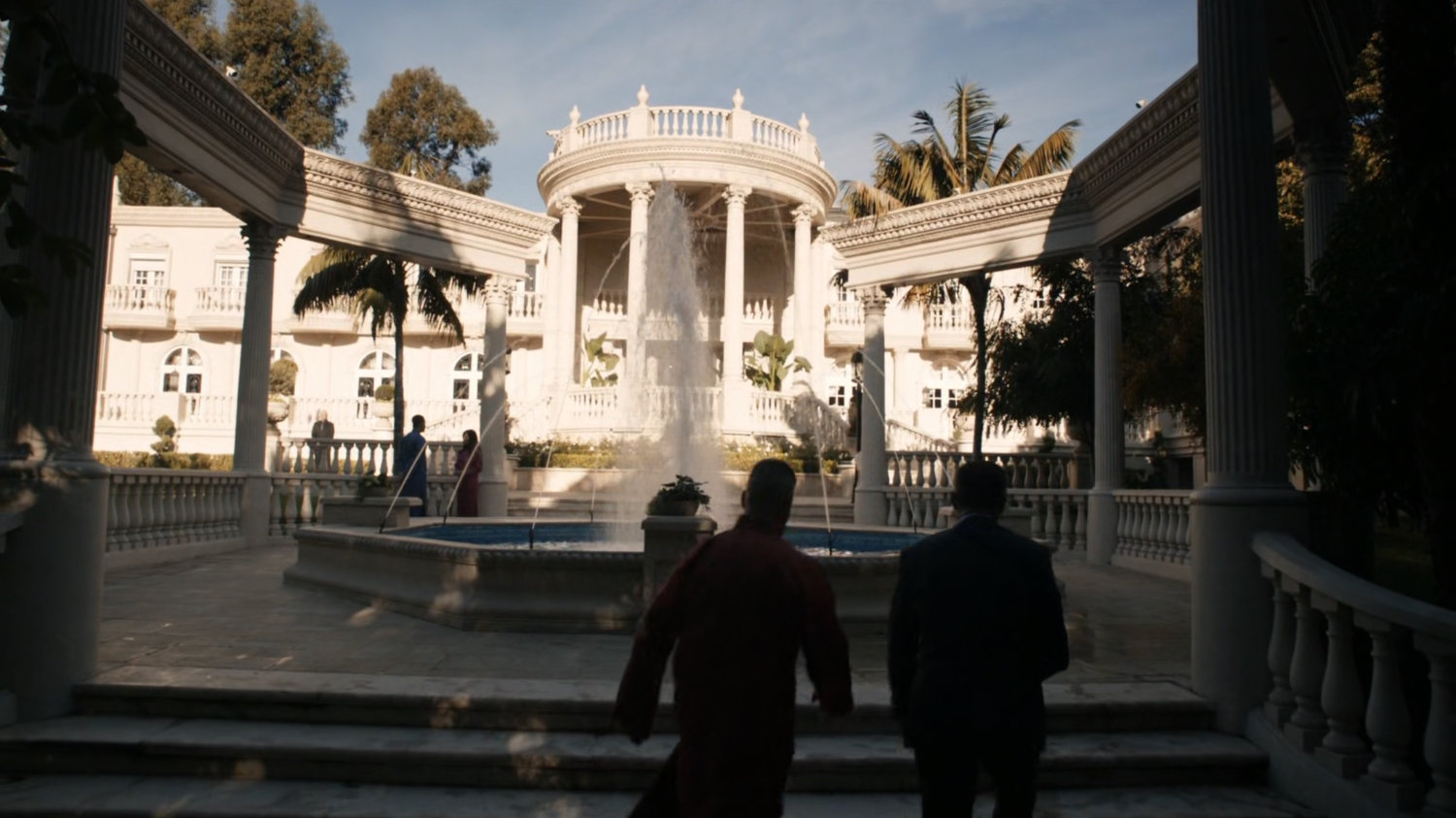 Coulson and Talbot walk past fountain in front of Taiwanese mansion.