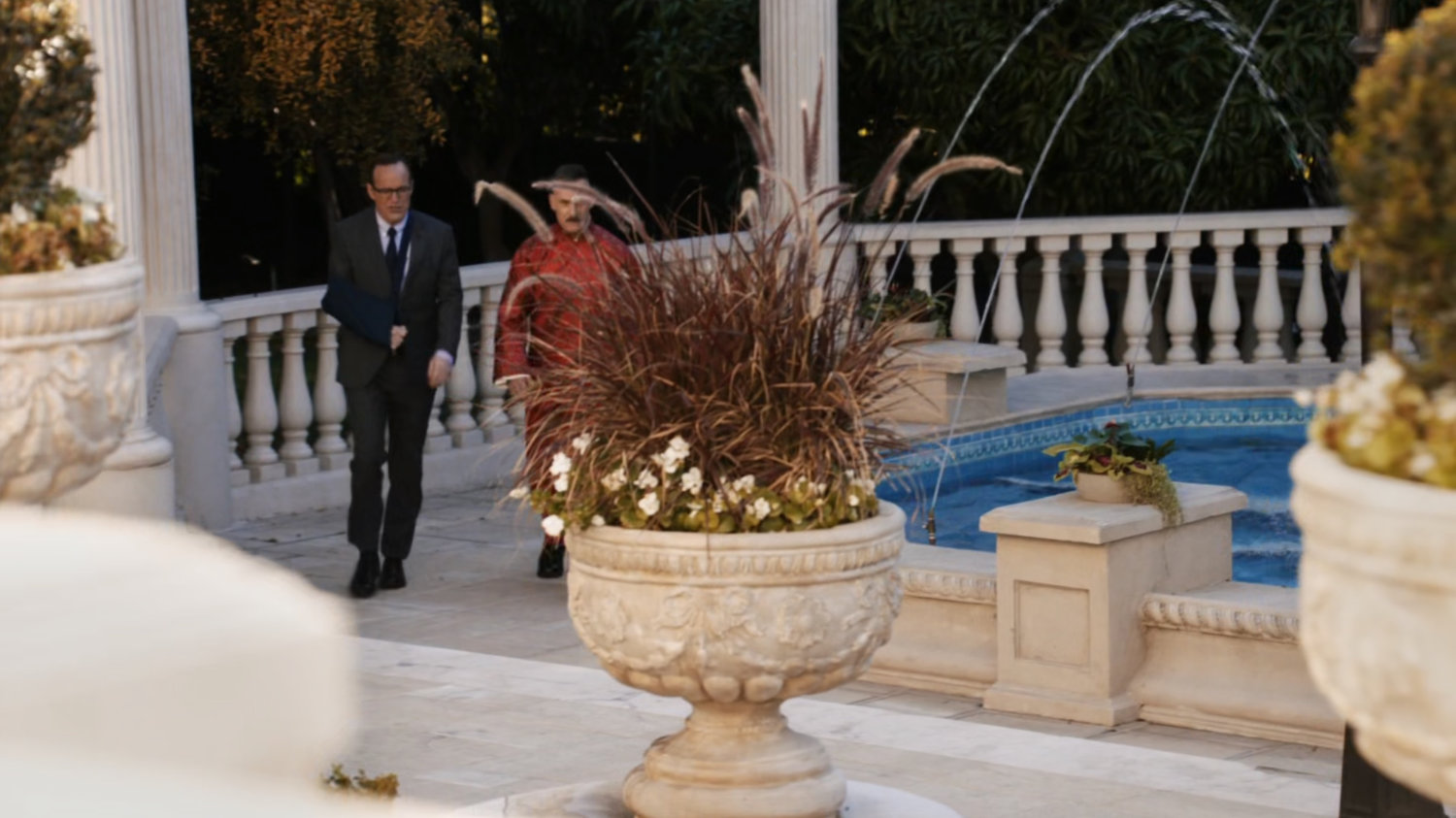 Coulson and Talbot walk past fountain in front of Taiwanese mansion.