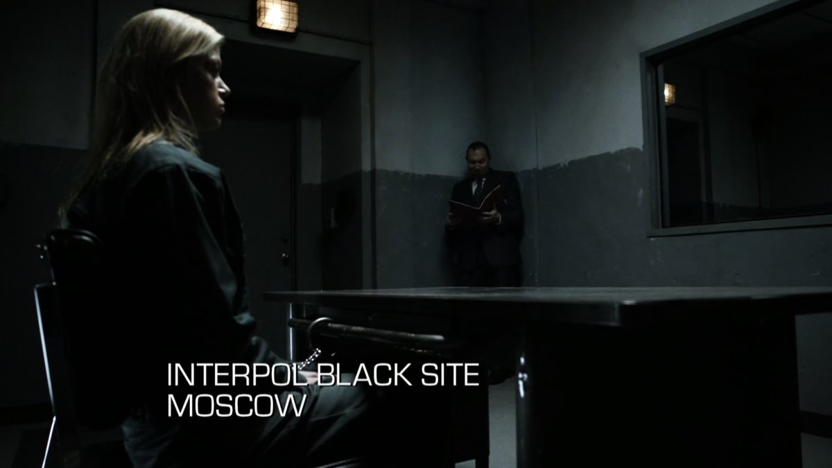 Bobbi in a small interrogation room. Text: Interpol Black Site, Moscow.