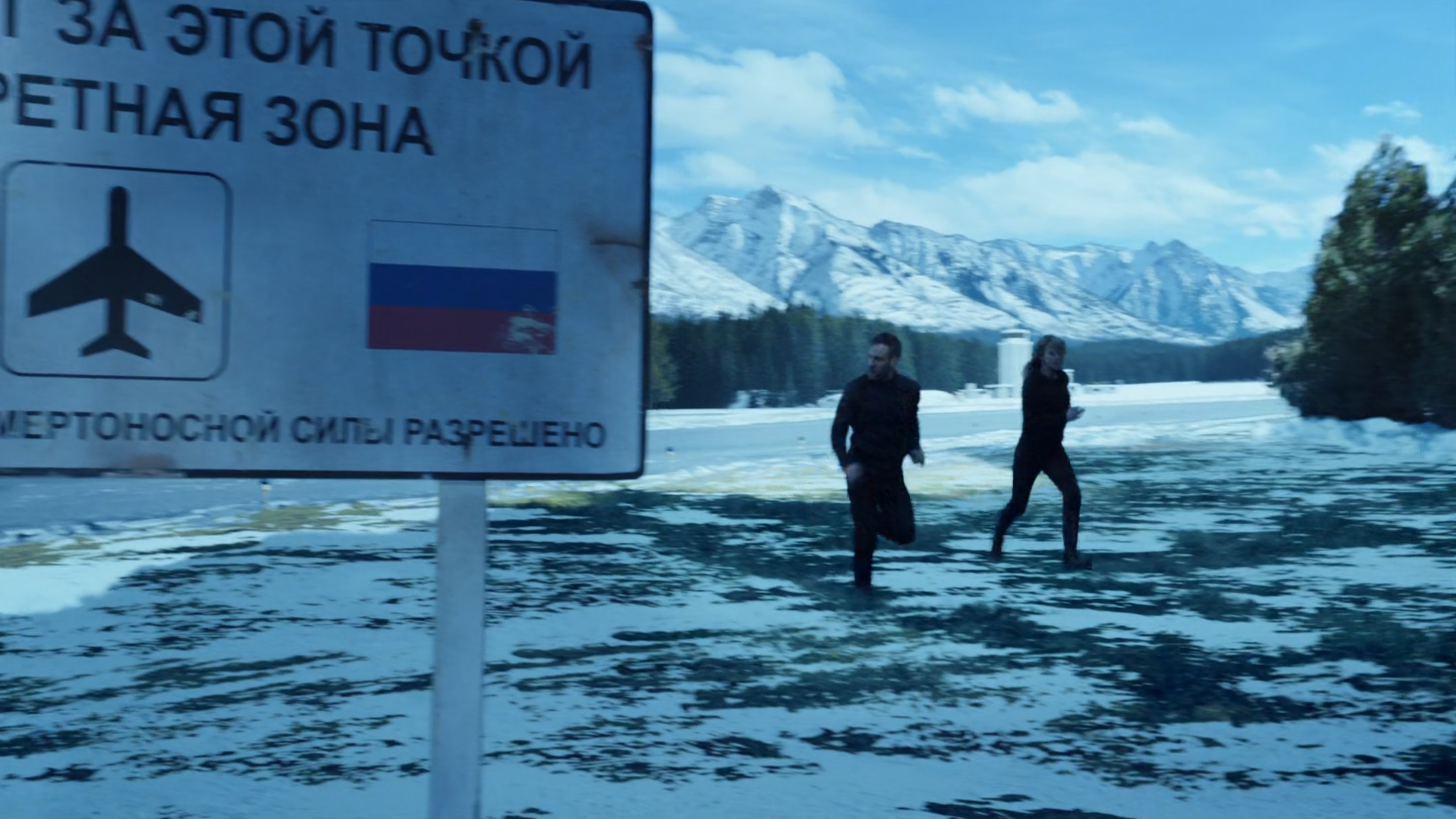 Hunter and Bobbi running past a Russian sign warning visitors not to trespass.