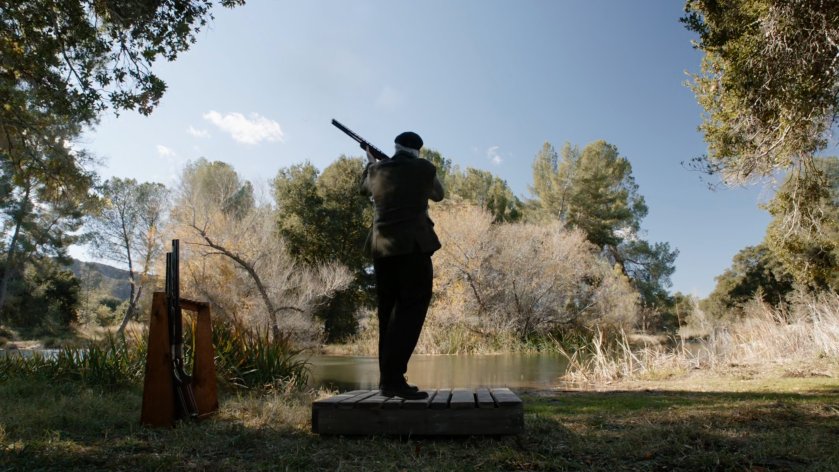 Malick shooting skeet by a lake.