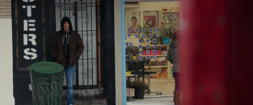 Wade in a hoodie standing on a sidewalk under an awning.