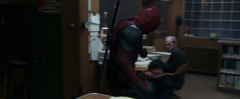 Deadpool beating up men in an office.