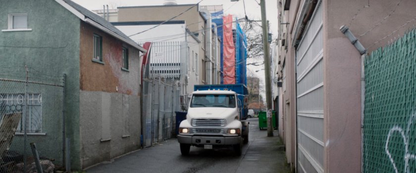 A trash truck driving through an alley.