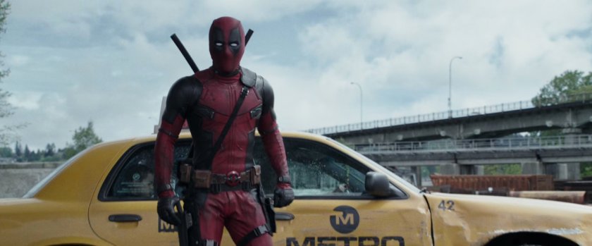 Deadpool exiting a taxi cab at a scrap yard.