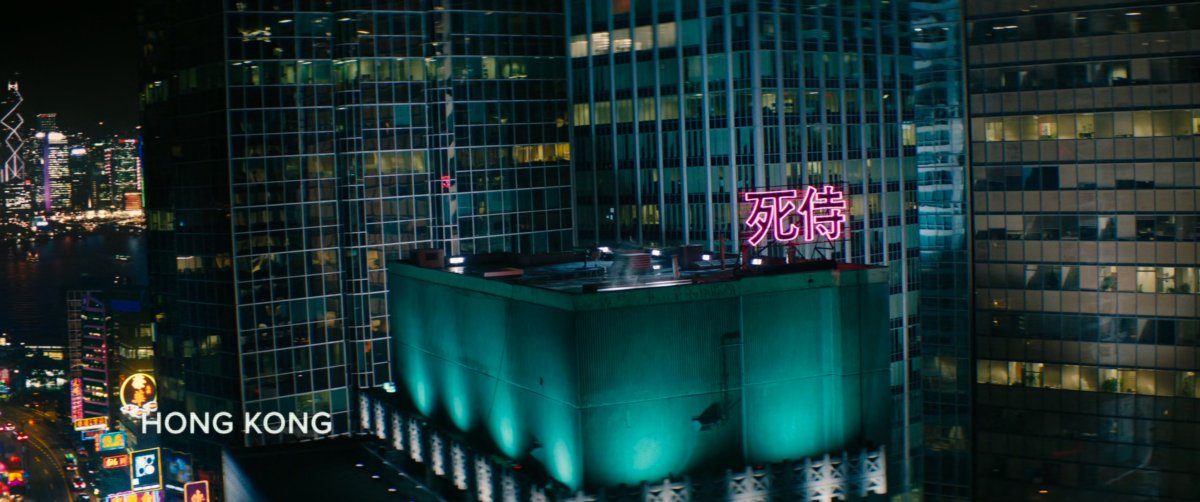 Aerial view of building in Hong Kong with a neon sign on the rooftop. Text: Hong Kong.