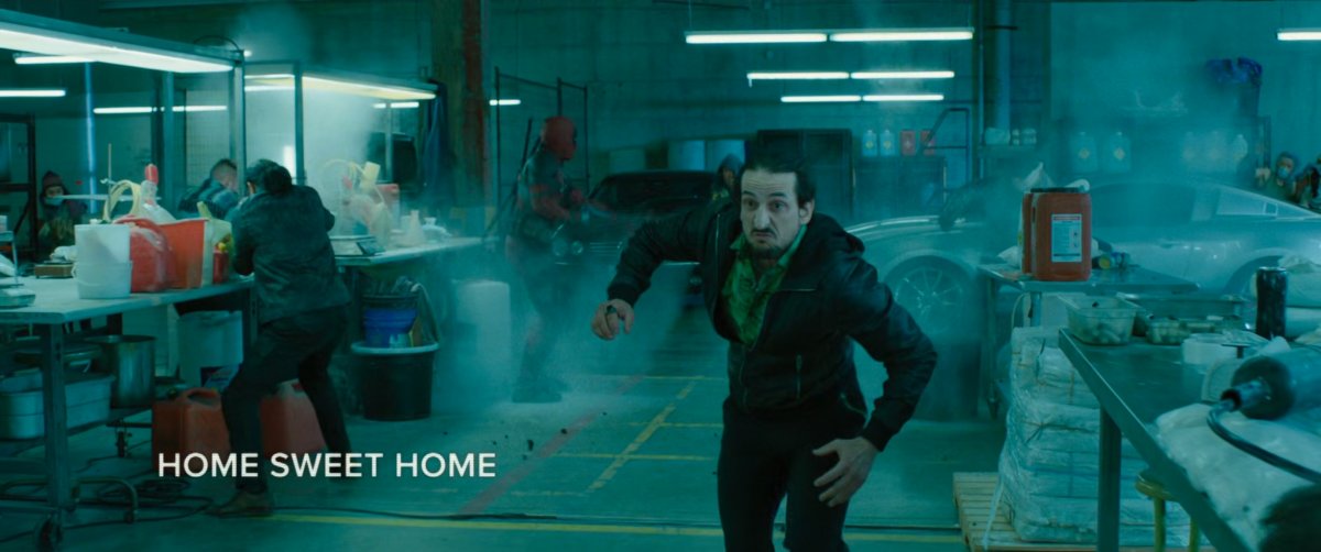 Deadpool shooting up the inside of a drug warehouse as a man runs away. Text: Home Sweet Home.