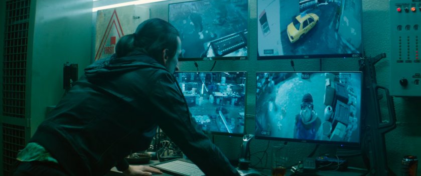 Man watching four video feeds on monitors.