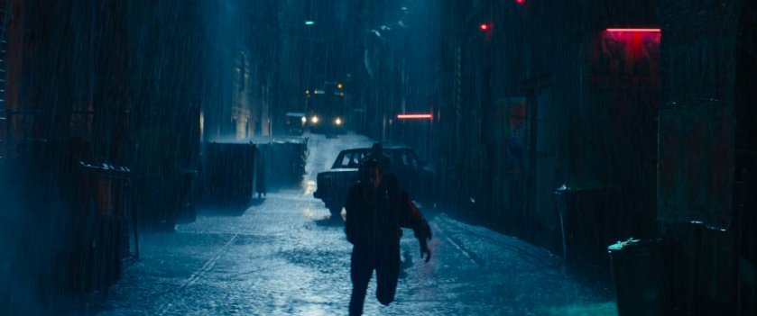 Wade chasing a man through a rainy alley.