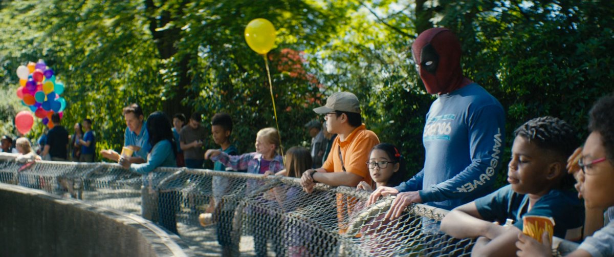 Deadpool standing at fence of Polar Bear enclosure with children.