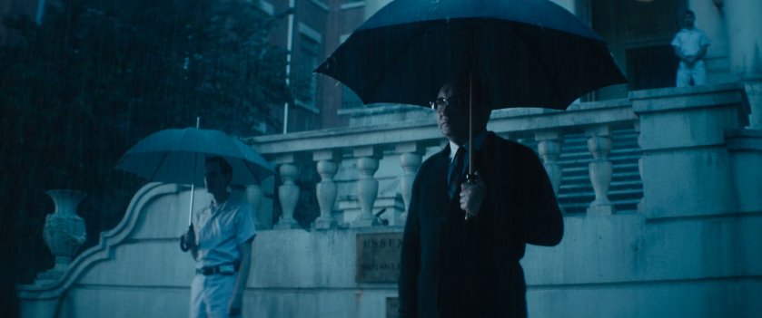 The headmaster of Essex House standing outside in the rain with an umbrella.