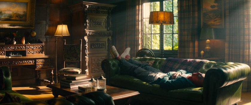 Deadpool laying on a couch in the study of the X-Mansion.
