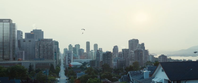 View of city with paraglider above it.