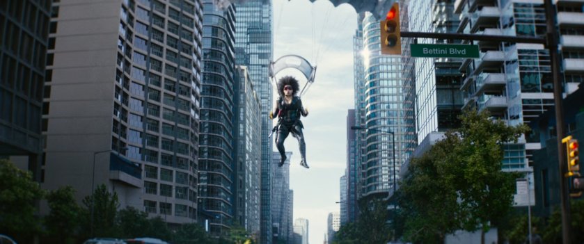 Domino parachutes towards city intersection.