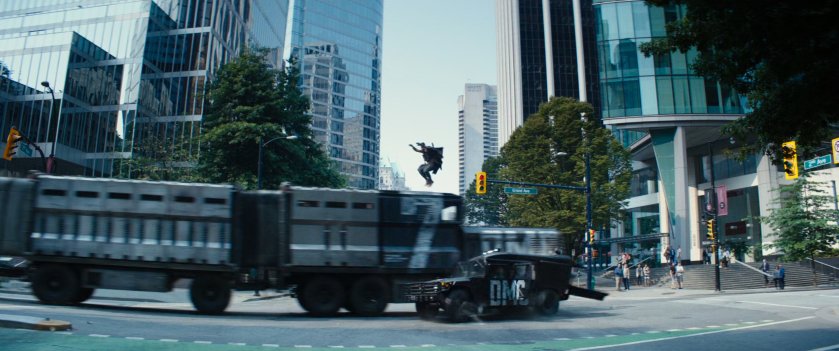 Cable leaping over convoy truck in city street.