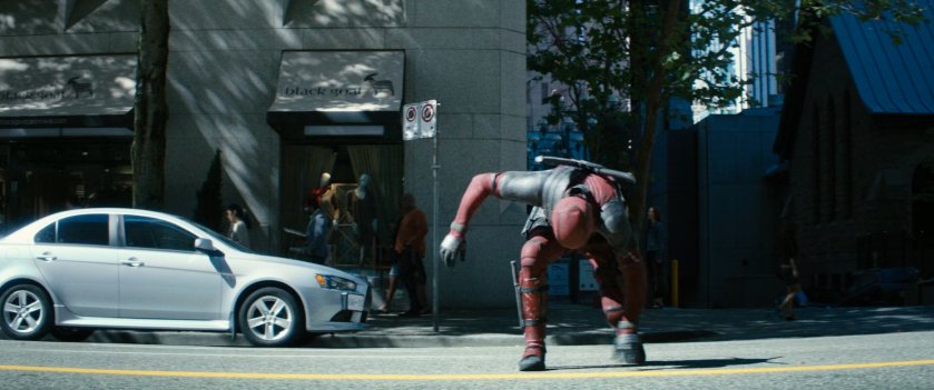 Deadpool standing back up in middle of street.