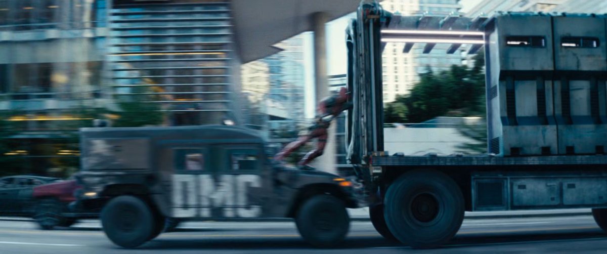 Deadpool jumping off truck onto prison convoy.