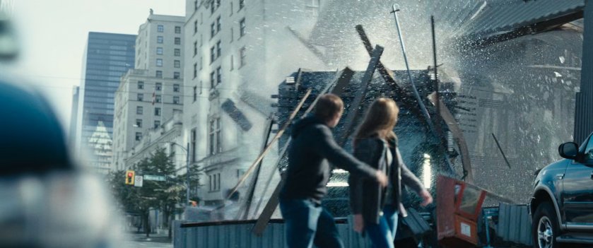 Prison convoy truck driving through building with two pedestrians watching.