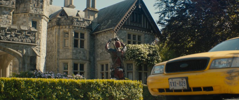 Deadpool playing music on iPhone outside X-Mansion.