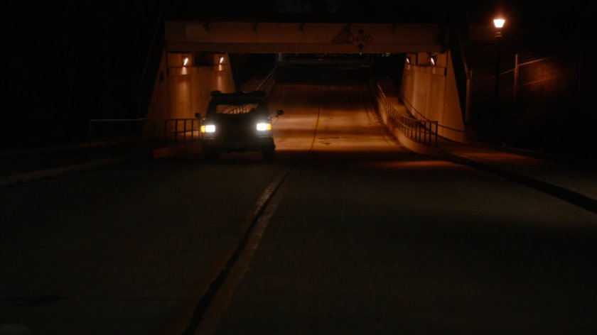Pickup truck driving under train bridge.