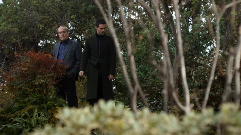 Hive and Gideon Malick standing near shrubs and trees.