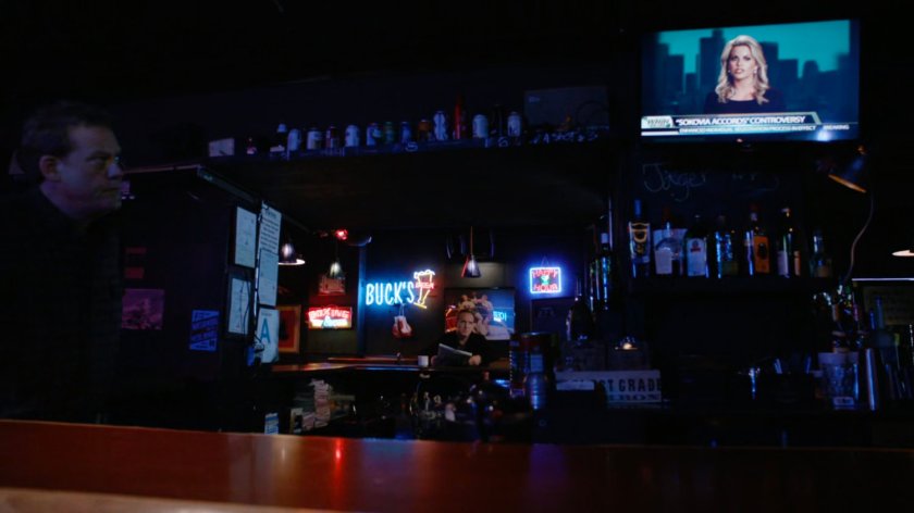 Coulson sitting inside a dark bar.