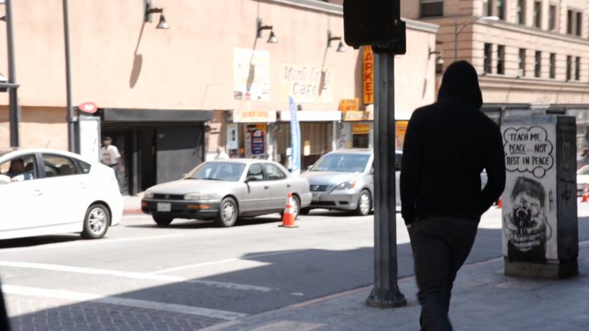 James walks around street corner.