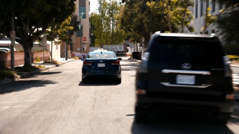 Coulson driving a SHIELD SUV along a city street.