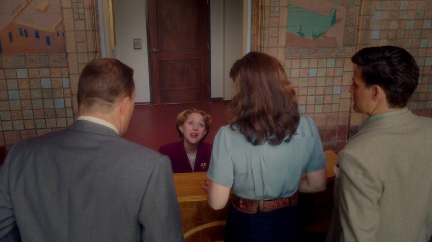 Sousa, Peggy, and Detective Henry speaking to receptionist in the Isodyne Energy lobby.
