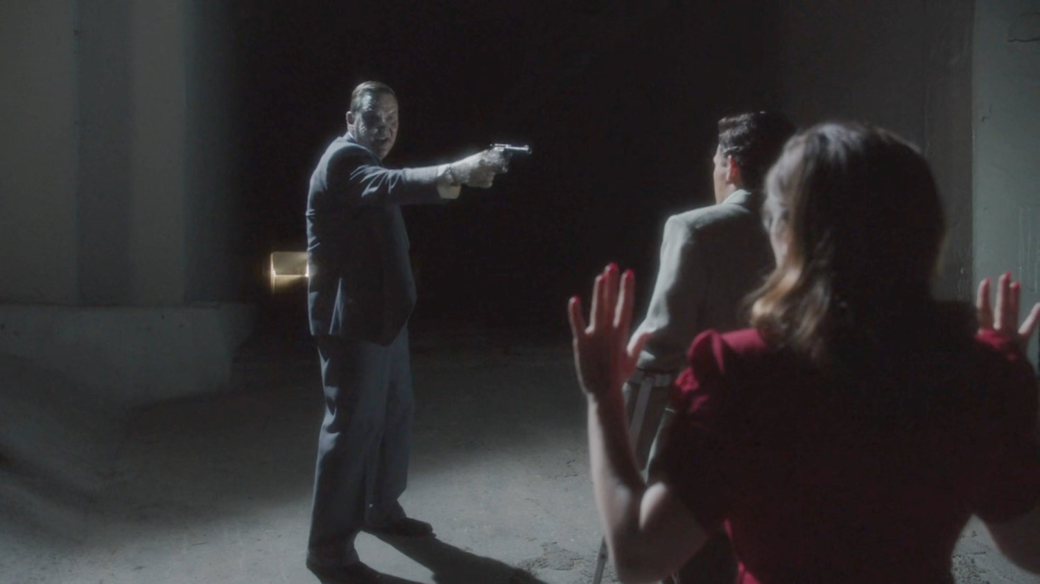 Detective Henry pointing gun at Sousa and Peggy.