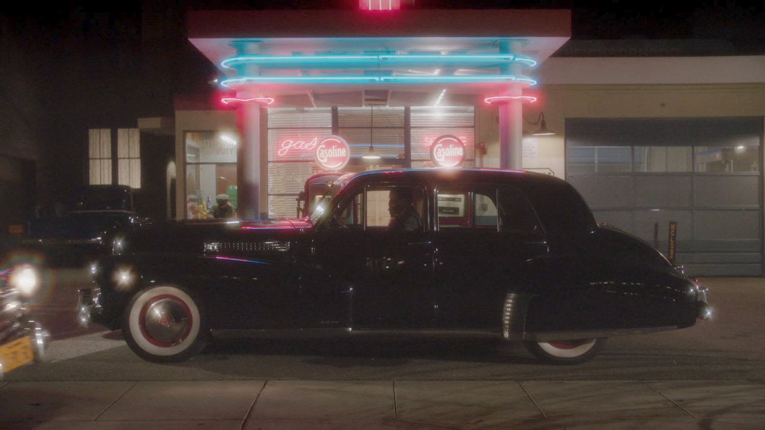 A car parked in front of a gas station with neon lighting.