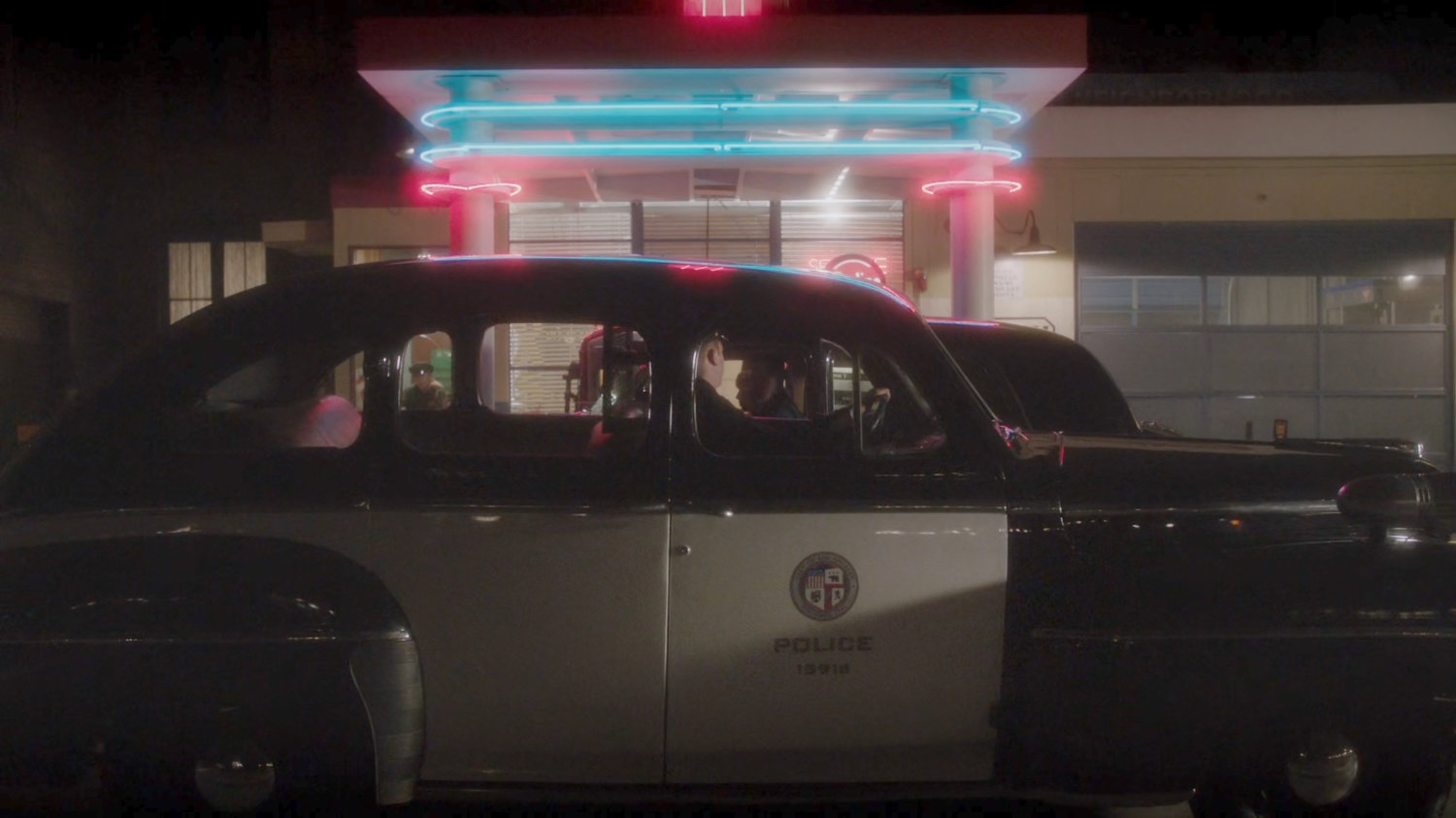 A police car in front of a gas station.
