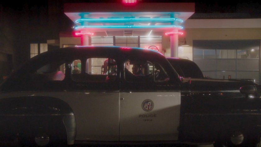 A police car in front of a gas station.