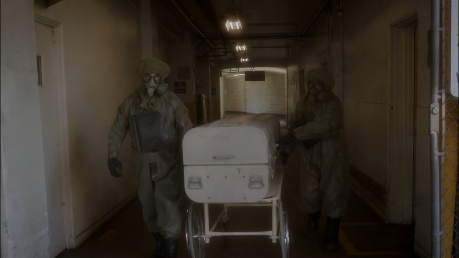 Two SSR agents in hazmat gear remove body from coroner's office.