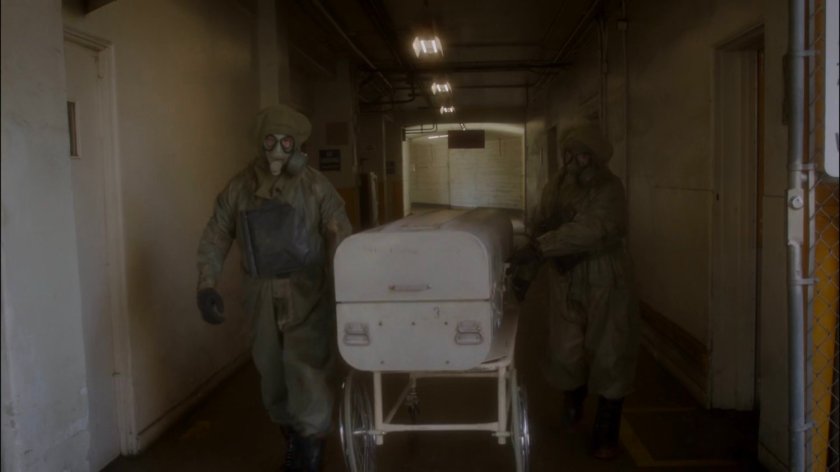 Two SSR agents in hazmat gear remove body from coroner's office.