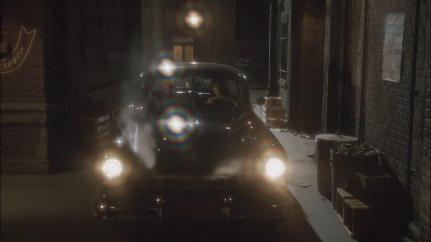 Car pulling into alley at night.