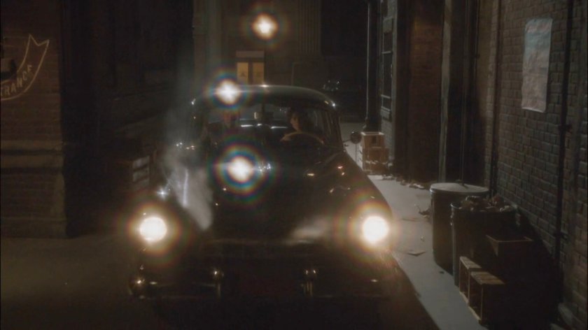 Car pulling into alley at night.