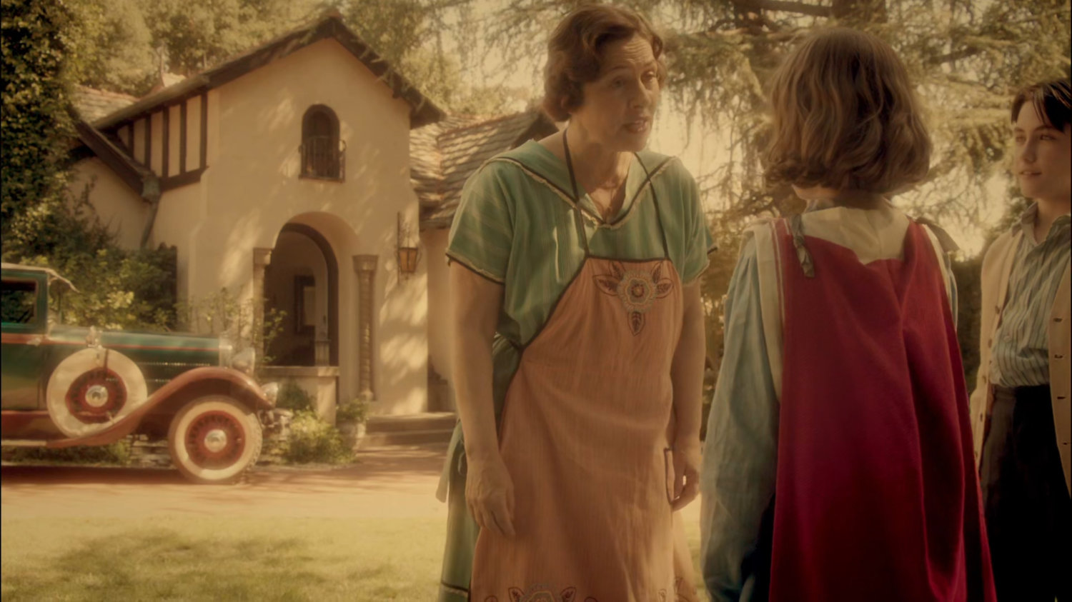 Young Peggy's mother talking to her in their yard.