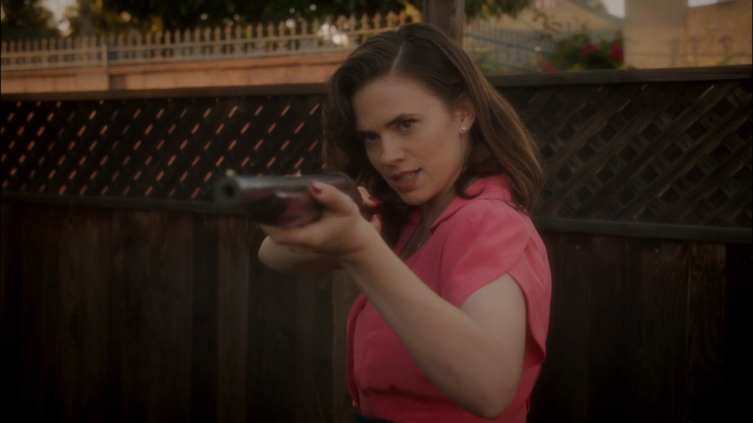 Peggy aims a shotgun at Rufus Hunt in his backyard.