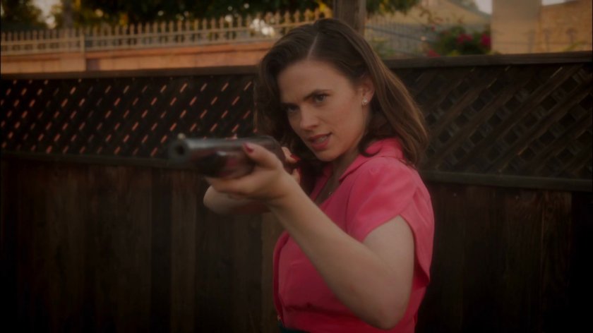 Peggy aims a shotgun at Rufus Hunt in his backyard.