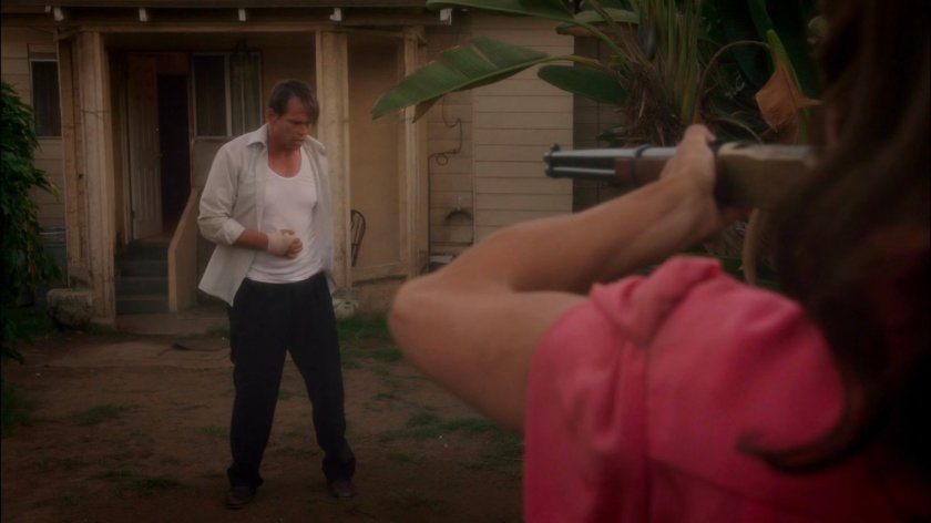 Peggy aims a shotgun at Rufus Hunt in his backyard.