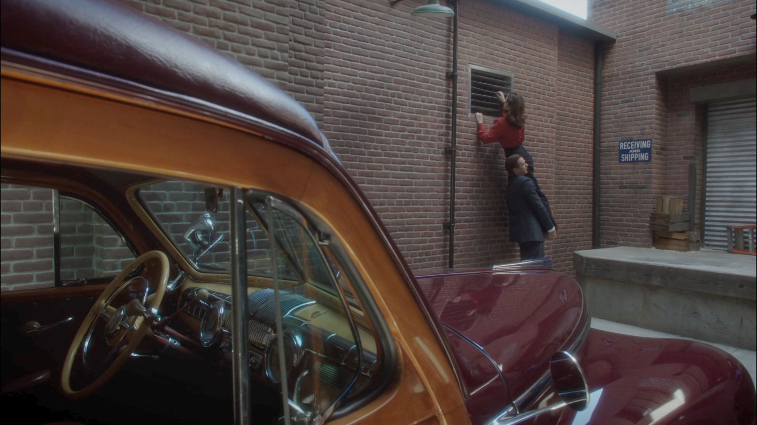 Jarvis helping Peggy into a vent in the alley behind the County Cold Storage building.