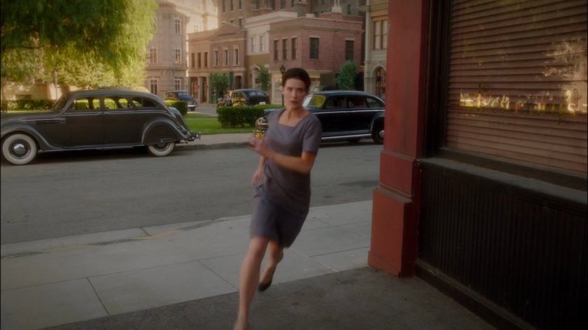 Dottie escapes the prison, running around a corner into an alley.