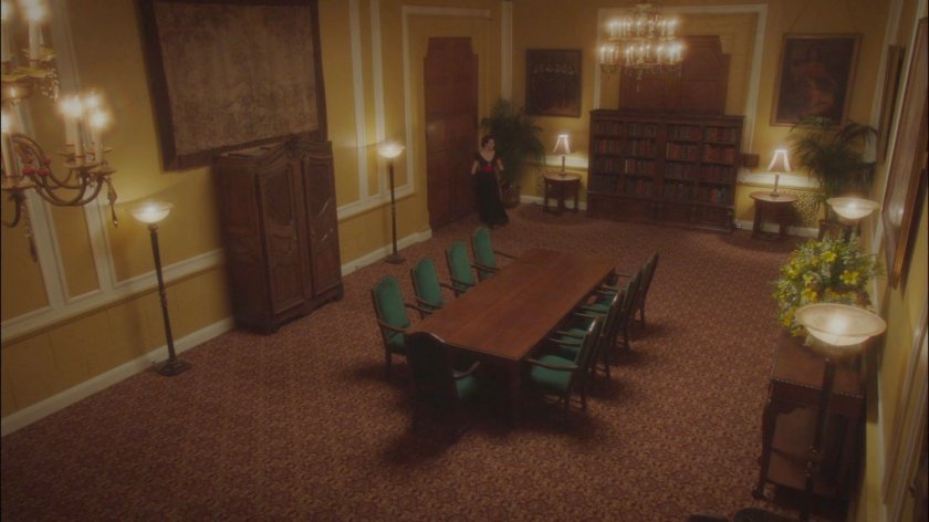 Dottie enters an empty meeting room in the MacArthur Grand Hotel.