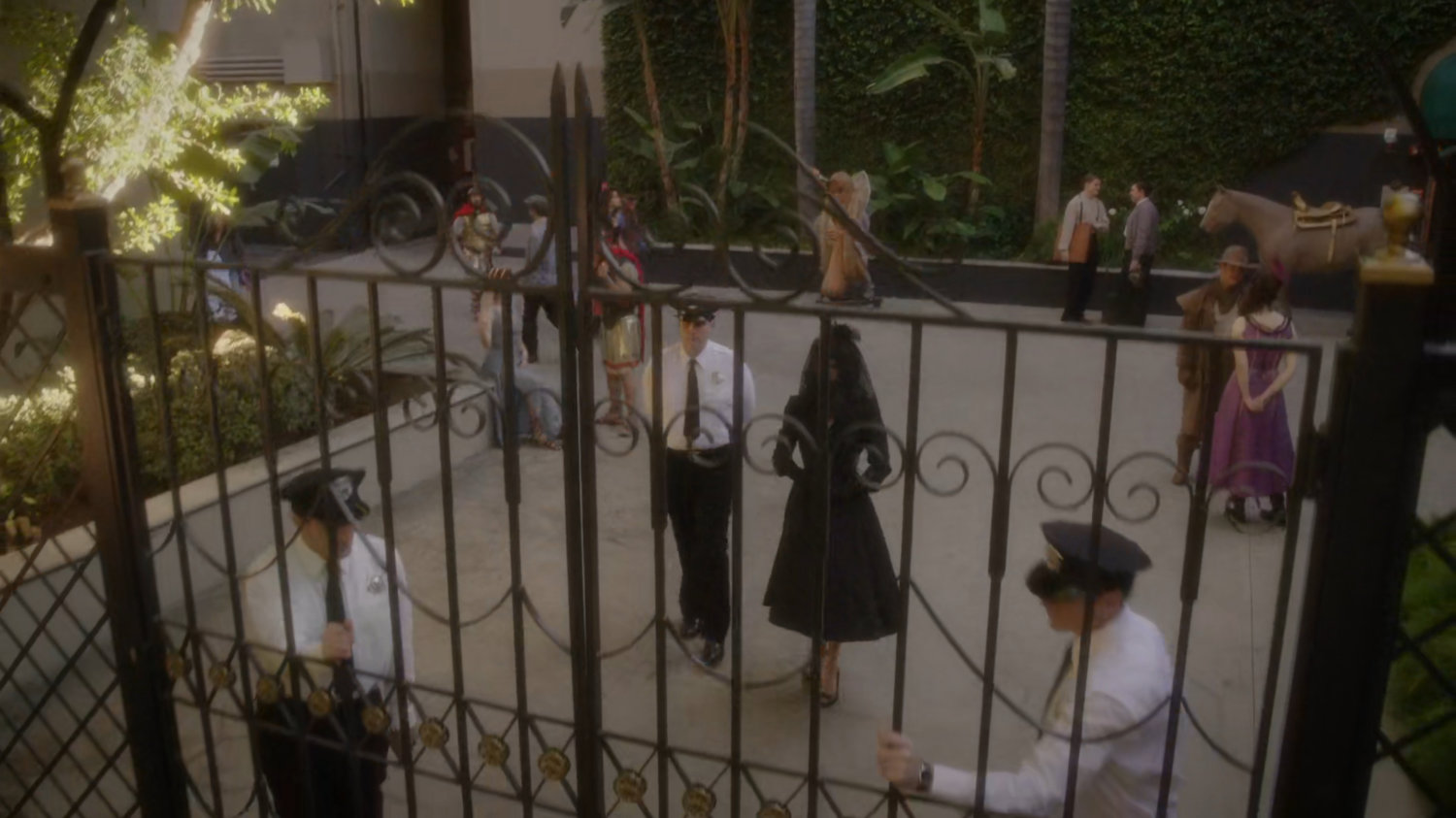 Whitney and guards walking towards front gate of Anvil Studios.