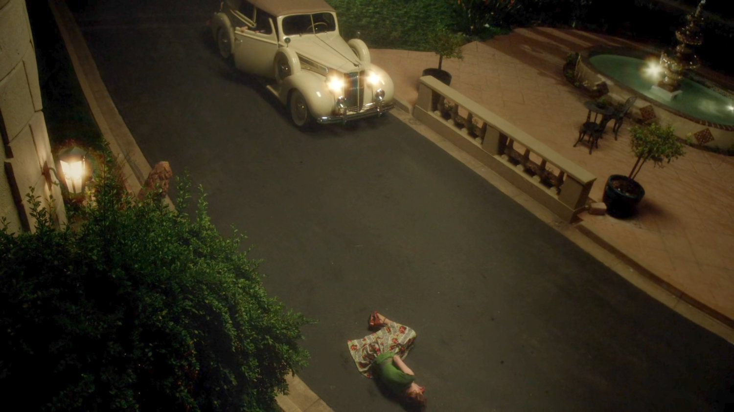 High angle view of Ana lying on driveway in front of Stark Mansion.
