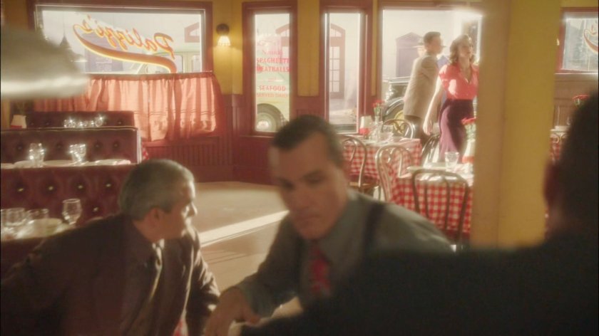 Men playing cards in Palizzi's restaurant as Peggy and Sousa enter.